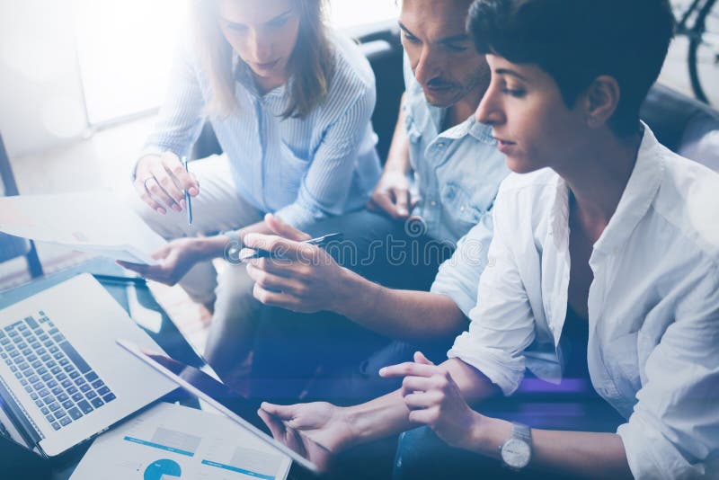 Drei junge Mitarbeiter, die an Laptop-Computer im Büro arbeiten Frau, die Tablette hält und auf Touch Screen zeigt horizontal lizenzfreie stockbilder Drei junge Mitarbeiter, die an Laptop-Computer im Büro arbeiten Frau, die Tablette hält und auf Touch Screen zeigt horizontal lizenzfreie stockbilder