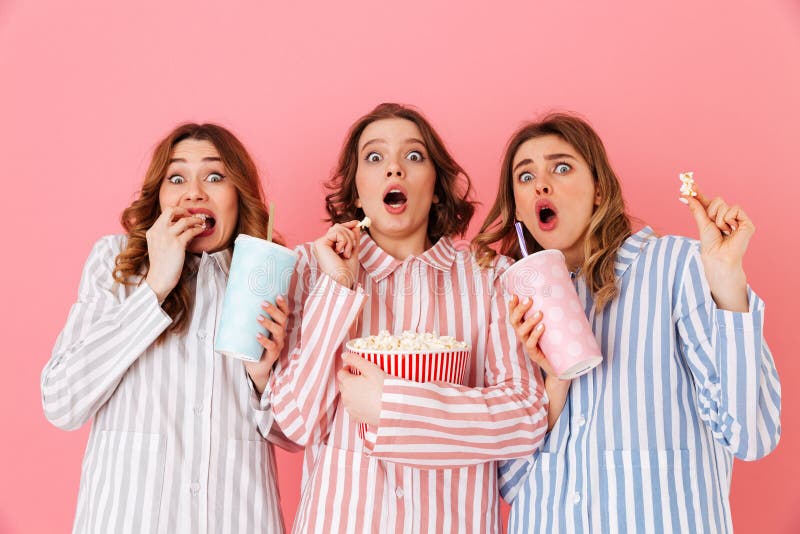 Drei junge Mädchen 20s, die buntes gestreiftes Pyjamas expressin tragen stockfoto Drei junge Mädchen 20s, die buntes gestreiftes Pyjamas expressin tragen stockfoto