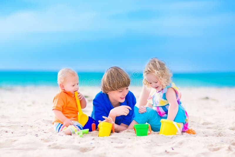 Drei Kinder, die auf einem Strand spielen lizenzfreies stockfoto Drei Kinder, die auf einem Strand spielen lizenzfreies stockfoto