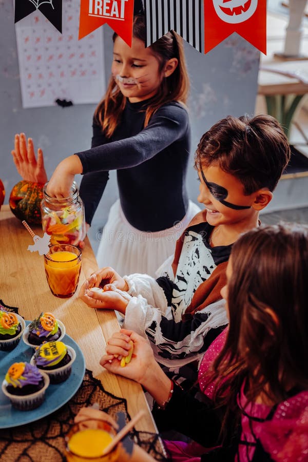 Drei Kinder, die kleine Kuchen beim Haben von Halloween-Partei im Kindergarten essen lizenzfreie stockfotografie Drei Kinder, die kleine Kuchen beim Haben von Halloween-Partei im Kindergarten essen lizenzfreie stockfotografie