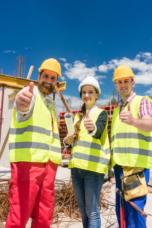 Drei Kollegen in einem Bauteam, das Daumen oben während der Arbeit zeigt stockbilder