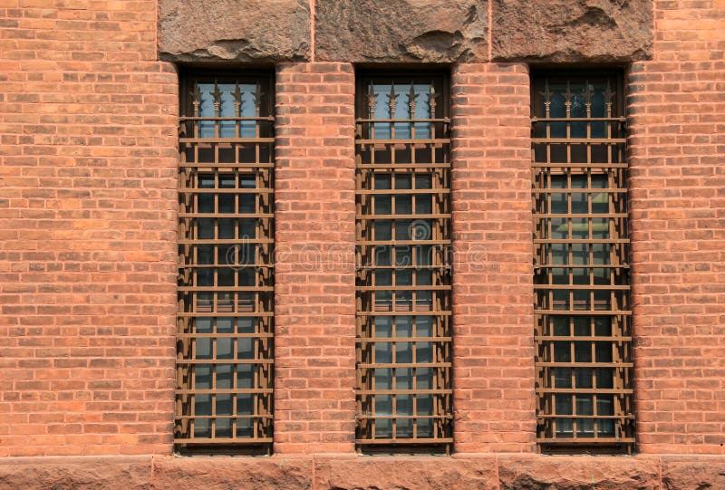 Drei lange Gitterfenster in der alten Backsteinmauer