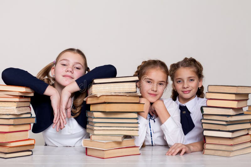 Drei Mädchen mit Schulbüchern für das Studium sitzen am Schreibtisch im Klassenzimmer stockbild