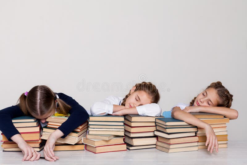 Drei Mädchen von Schulmädchen mit Büchern schlafen an einem Schreibtisch im Klassenzimmer lizenzfreie stockfotos