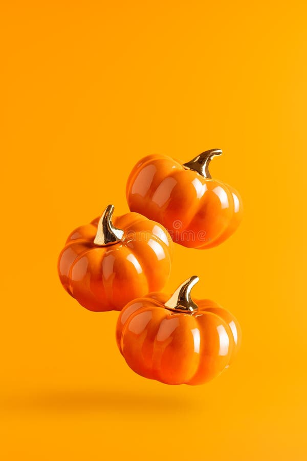 Drei schwebende Keramikkürbis auf orangefarbenem Hintergrund. Vertikalbanner lizenzfreies stockbild
