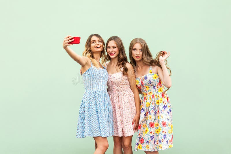 Drei schöne Schwestern im Kleid, macking selfie auf grünem Hintergrund, lizenzfreie stockbilder Drei schöne Schwestern im Kleid, macking selfie auf grünem Hintergrund, lizenzfreie stockbilder