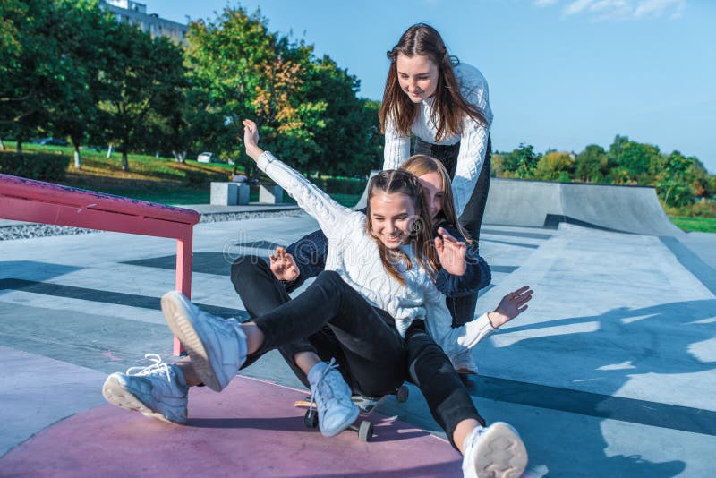 Drei Teenagerinnen fahren Skateboard, Spaß beim Spielen und Lachen, Sommersportplatz, in warmer Atmosphäre stockfotos
