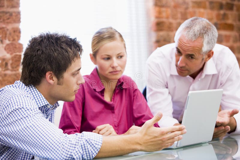 Drei Wirtschaftler im Büro mit Laptop lizenzfreie stockfotos Drei Wirtschaftler im Büro mit Laptop lizenzfreie stockfotos