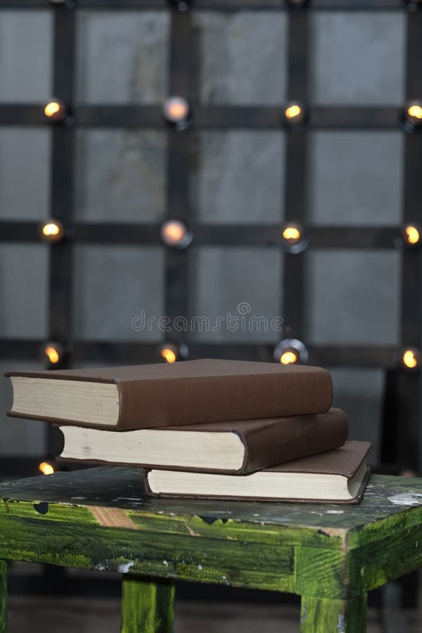 Tree big books on chair near old edison lamps mounted on wooden background. Tree big books on chair near old edison lamps mounted on wooden background