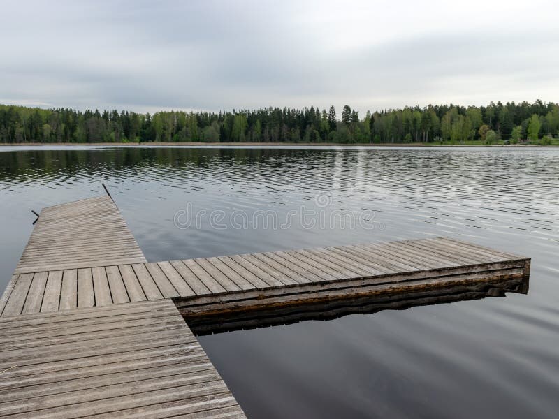 Drewniany kładka w pustej plaży jeziora, wiosną ubiegłych lat, trzciny i pierwsza zieleń obraz stock