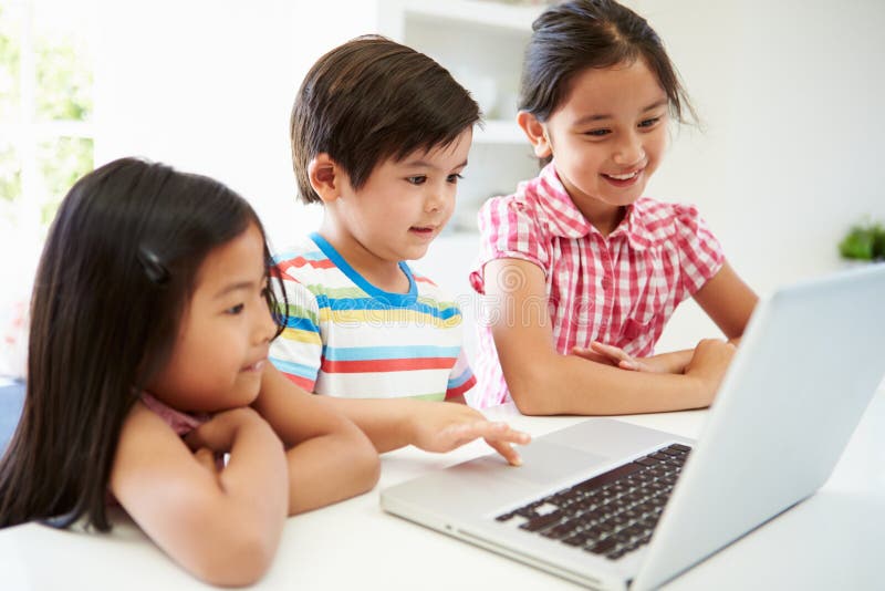 Drie Aziatische Kinderen die Laptop thuis met behulp van royalty-vrije stock fotografie Drie Aziatische Kinderen die Laptop thuis met behulp van royalty-vrije stock fotografie