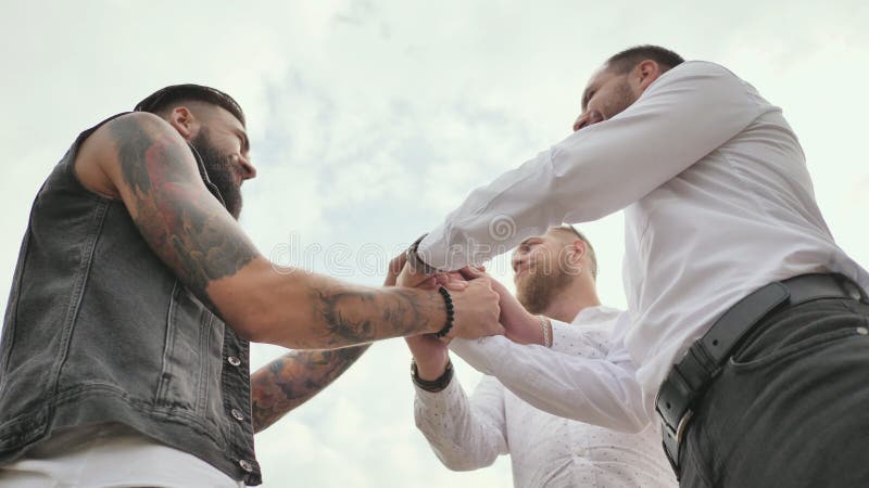 Drie brutale mensen met een baard begroeten elkaar met een handdruk