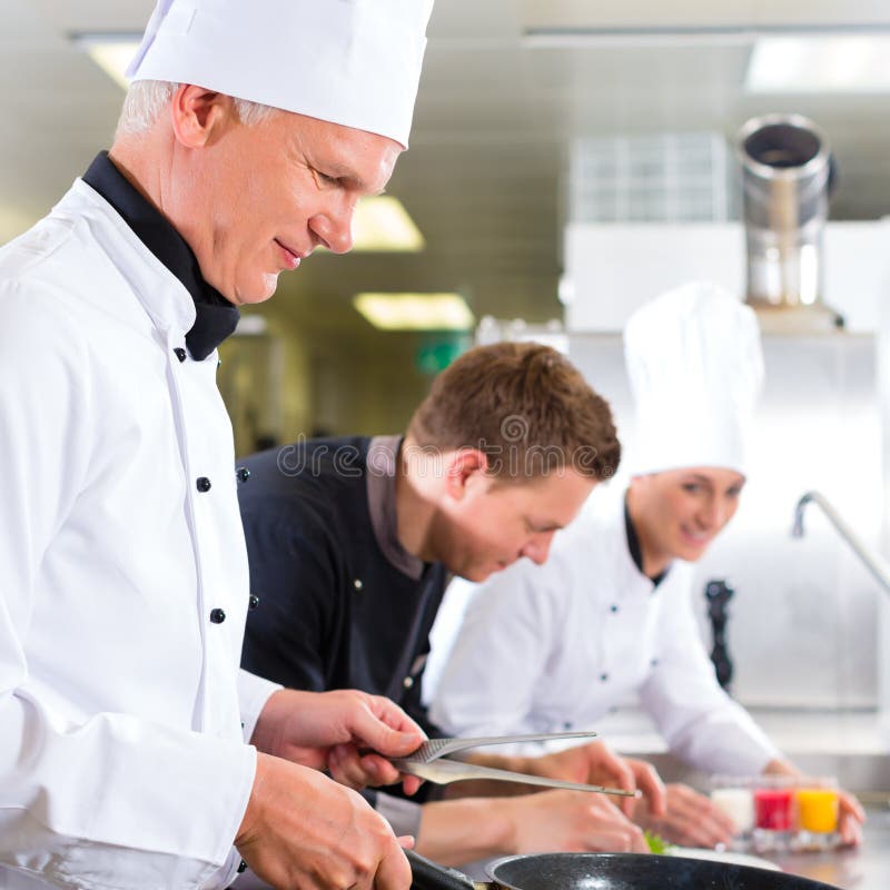 Drie chef-koks in team in hotel of restaurantkeuken