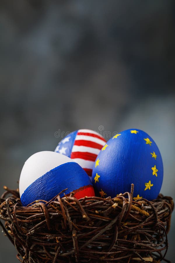 Drie die paaseieren in een nest in kleuren van de vlaggen van de Europese Unie van Rusland, van Amerika wordt geschilderd en stock foto Drie die paaseieren in een nest in kleuren van de vlaggen van de Europese Unie van Rusland, van Amerika wordt geschilderd en stock foto