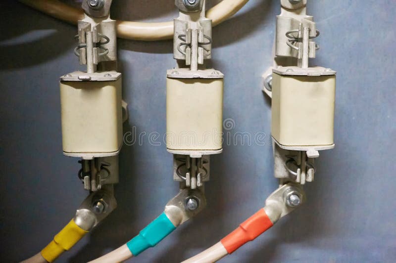 Drie elektrozekeringen met hoog voltage die aan de gekleurde draden worden aangesloten Industriële Achtergrond stock afbeelding Drie elektrozekeringen met hoog voltage die aan de gekleurde draden worden aangesloten Industriële Achtergrond stock afbeelding