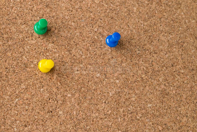 Drie Gekleurde Duimkopspijkers op Cork Board stock afbeeldingen Drie Gekleurde Duimkopspijkers op Cork Board stock afbeeldingen