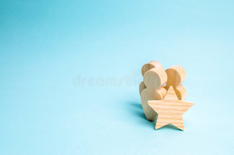 Drie houten cijfers van mensen en een ster Teken van verschil, positieve evaluatie, beloning voor de voltooiing van taken en verw stock fotografie Drie houten cijfers van mensen en een ster Teken van verschil, positieve evaluatie, beloning voor de voltooiing van taken en verw stock fotografie