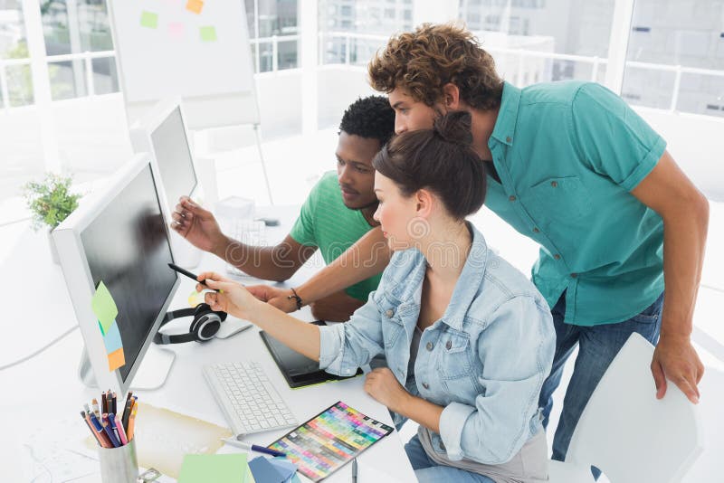 Drie kunstenaars die aan computer op kantoor werken royalty-vrije stock foto Drie kunstenaars die aan computer op kantoor werken royalty-vrije stock foto
