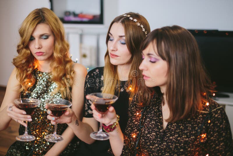 Drie meisjes die hun dranken bij een partij, nadruk op het meisje controleren stock afbeelding Drie meisjes die hun dranken bij een partij, nadruk op het meisje controleren stock afbeelding