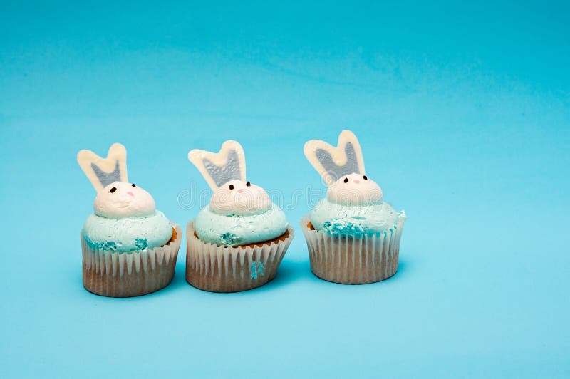 Drie paasmuffins op een blauwe achtergrond. Minimalistische compositie, ruimte voor tekst stock foto's