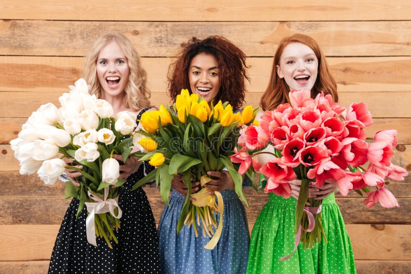 Drie vrouwen die boeketten van bloemen tonen bij camera royalty-vrije stock foto's Drie vrouwen die boeketten van bloemen tonen bij camera royalty-vrije stock foto's