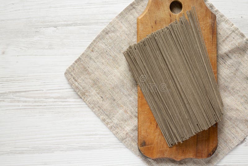 Dried buckwheat soba noodles on rustic wooden board over white wooden background, top view. Copy space royalty free stock image Dried buckwheat soba noodles on rustic wooden board over white wooden background, top view. Copy space royalty free stock image