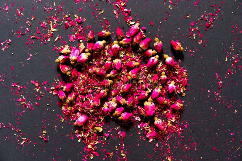 Dried buds of pink roses on a black background. Place for text. Flat lay. greeting card. Filler for the taste and aroma of tea. Modern flat wedding invitation stock photos Dried buds of pink roses on a black background. Place for text. Flat lay. greeting card. Filler for the taste and aroma of tea. Modern flat wedding invitation stock photos