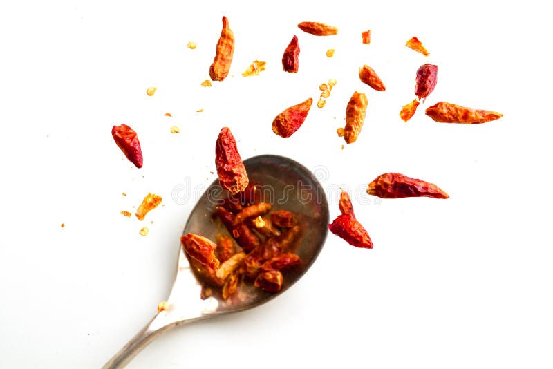 Dried chili peppers jumping from a spoon, isolated on white, health concept capsaicin