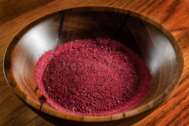 Dried and crushed red peppers, wooden plate on wooden table. stock photos