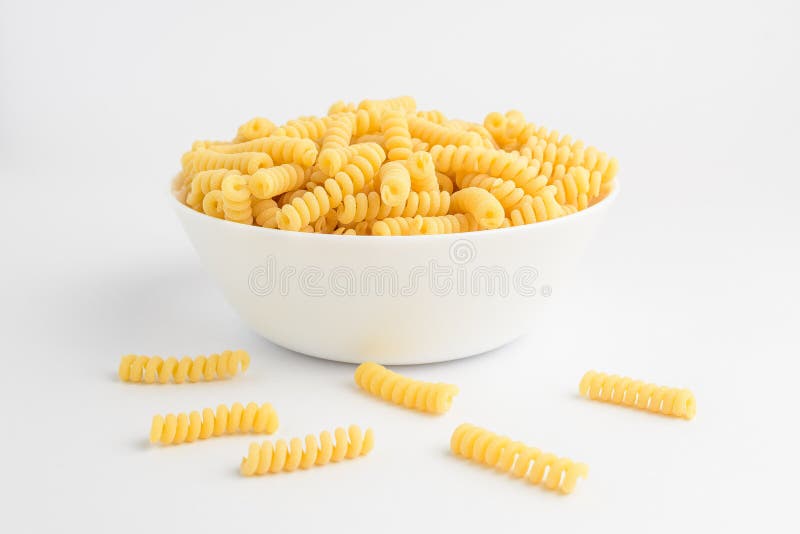 Dried fusili Italian pasta in a round bowl ready to be cooked, isolated on a white table, with side view