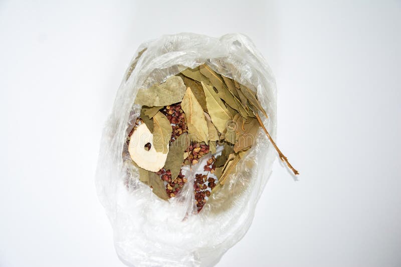 Dried laurel leaves, Sichuan peppercorns (Zanthoxylum simulans), and Bai Zhi slices (Angelica dahurica) are inside a clear plastic bag. The laurel leaves are greenish-brown, flat, and oval-shaped. Sichuan peppercorns are small, reddish-brown spheres. Bai Zhi slices are circular, cream-colored, and thin. These spices and herbs are commonly used in Chinese cooking and traditional medicine, providing distinct flavors and aromatic properties. The packaging is simple, suitable for storage and transport. Circular slices stock images, royalty-free photos and pictures