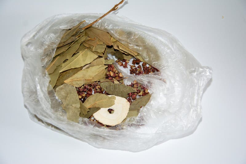 Dried laurel leaves, Sichuan peppercorns (Zanthoxylum simulans), and Bai Zhi slices (Angelica dahurica) are inside a clear plastic bag. The laurel leaves are greenish-brown, flat, and oval-shaped. Sichuan peppercorns are small, reddish-brown spheres. Bai Zhi slices are circular, cream-colored, and thin. These spices and herbs are commonly used in Chinese cooking and traditional medicine, providing distinct flavors and aromatic properties. The packaging is simple, suitable for storage and transport. Circular slices stock images, royalty-free photos and pictures