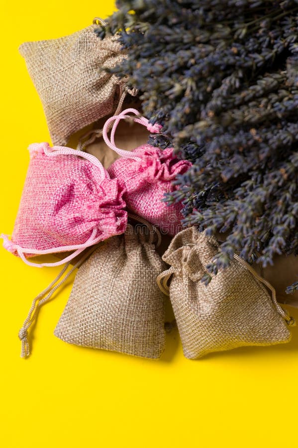 Dried lavender flowers and sachets on yellow background, lavender aromatherapy. Dried lavender flowers and sachets on yellow background, lavender aromatherapy.