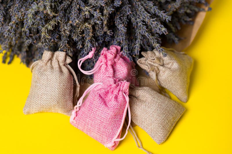 Dried lavender flowers and sachets on yellow background, lavender aromatherapy. Dried lavender flowers and sachets on yellow background, lavender aromatherapy.