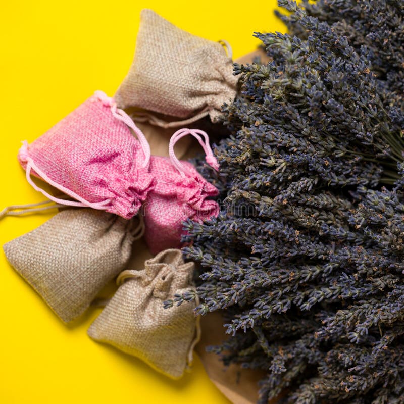 Dried lavender flowers and sachets on yellow background, lavender aromatherapy. Dried lavender flowers and sachets on yellow background, lavender aromatherapy.