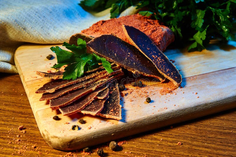 Dried meat, basturma lies on a wooden Board with capers and spices. fresh parsley royalty free stock photography Dried meat, basturma lies on a wooden Board with capers and spices. fresh parsley royalty free stock photography