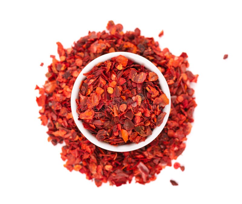 Dried red chili flakes in bowl, isolated on white background. Chopped chilli cayenne pepper. Spices and herbs. Top view.