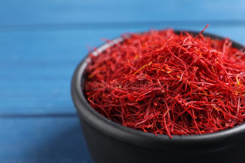 Dried saffron in bowl on blue table, closeup stock photos