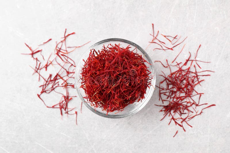 Dried saffron and glass bowl on grey table, flat lay stock photography
