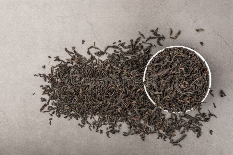 Dried tea is poured into a white ceramic cup on a gray textured background. View from above. Layout royalty free stock photo Dried tea is poured into a white ceramic cup on a gray textured background. View from above. Layout royalty free stock photo