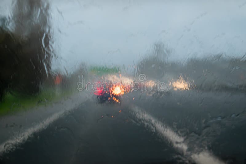 Driving with heavy rain on car windscreen on State Highway 1, Auckland, New Zealand, NZ - car in front is indicating. Driving with heavy rain on car windscreen on State Highway 1, Auckland, New Zealand, NZ - car in front is indicating