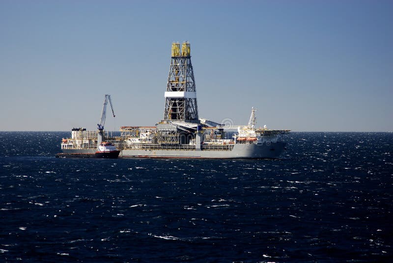 A drill ship working in deepwater takes on supplies from a work boat. A drill ship working in deepwater takes on supplies from a work boat.