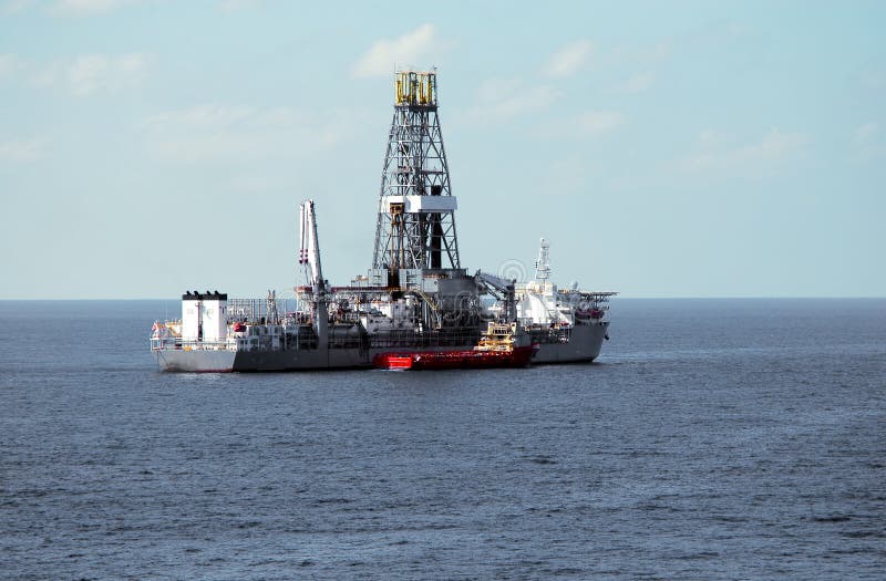 A drill ship working in deepwater takes on supplies from a work boat. A drill ship working in deepwater takes on supplies from a work boat.