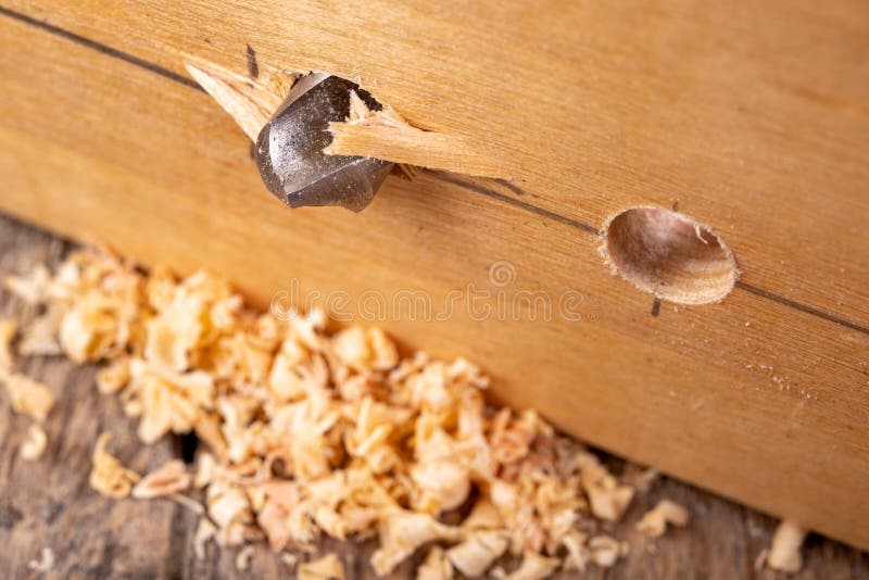Drilling in a piece of wood with a metal drill bit. Small carpentry work in a home workshop