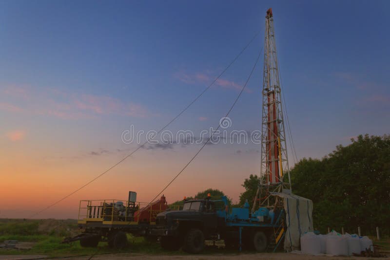 Drilling rig drills a well for the extraction of drinking water at sunset under a beautiful sky for drinking people stock photos