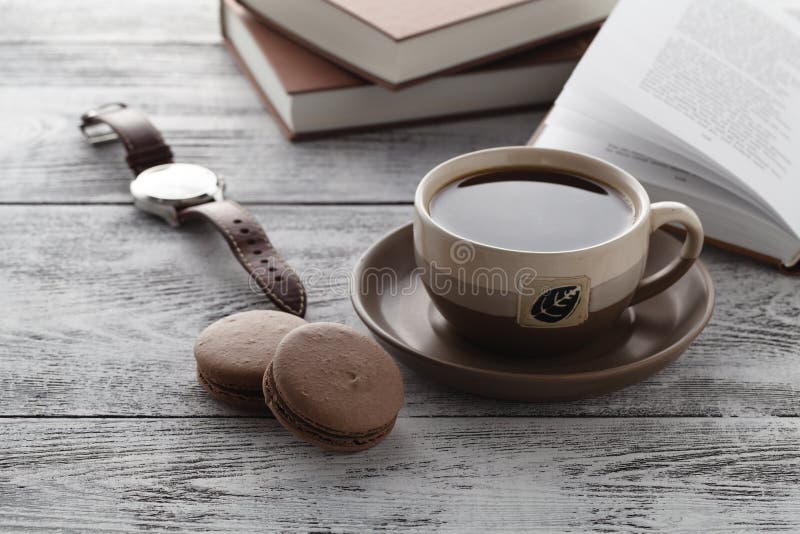 Drink coffee while reading book on table. Interior, morning.