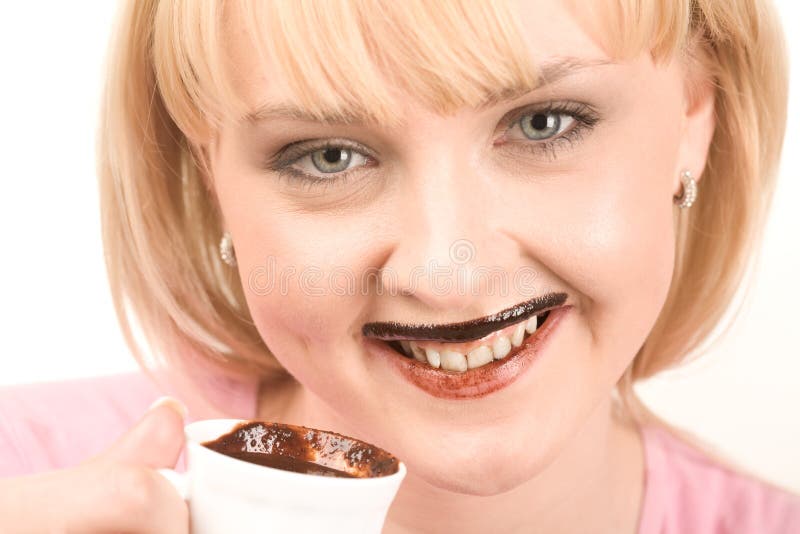 Close-up of pretty girl enjoying hot chocolate and smiling at camera. Close-up of pretty girl enjoying hot chocolate and smiling at camera