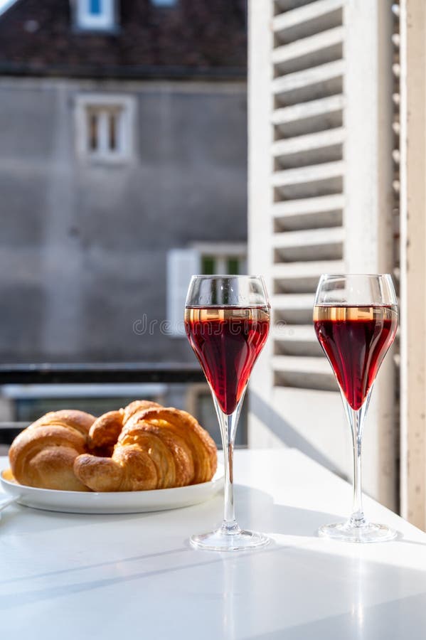 Drinking of Kir Royal,  French aperitif cocktail made  from creme de cassis topped with champagne, typically served in flute glass