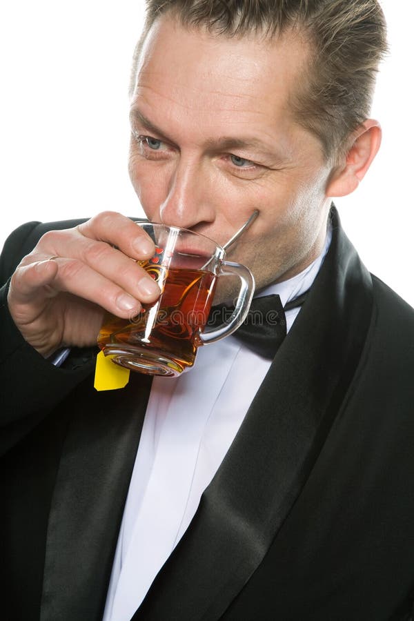 A man in a tuxedo drinking tea