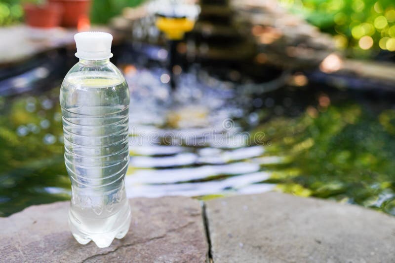Drinking Water Pouring from Bottle on Blurred Green Nature Background